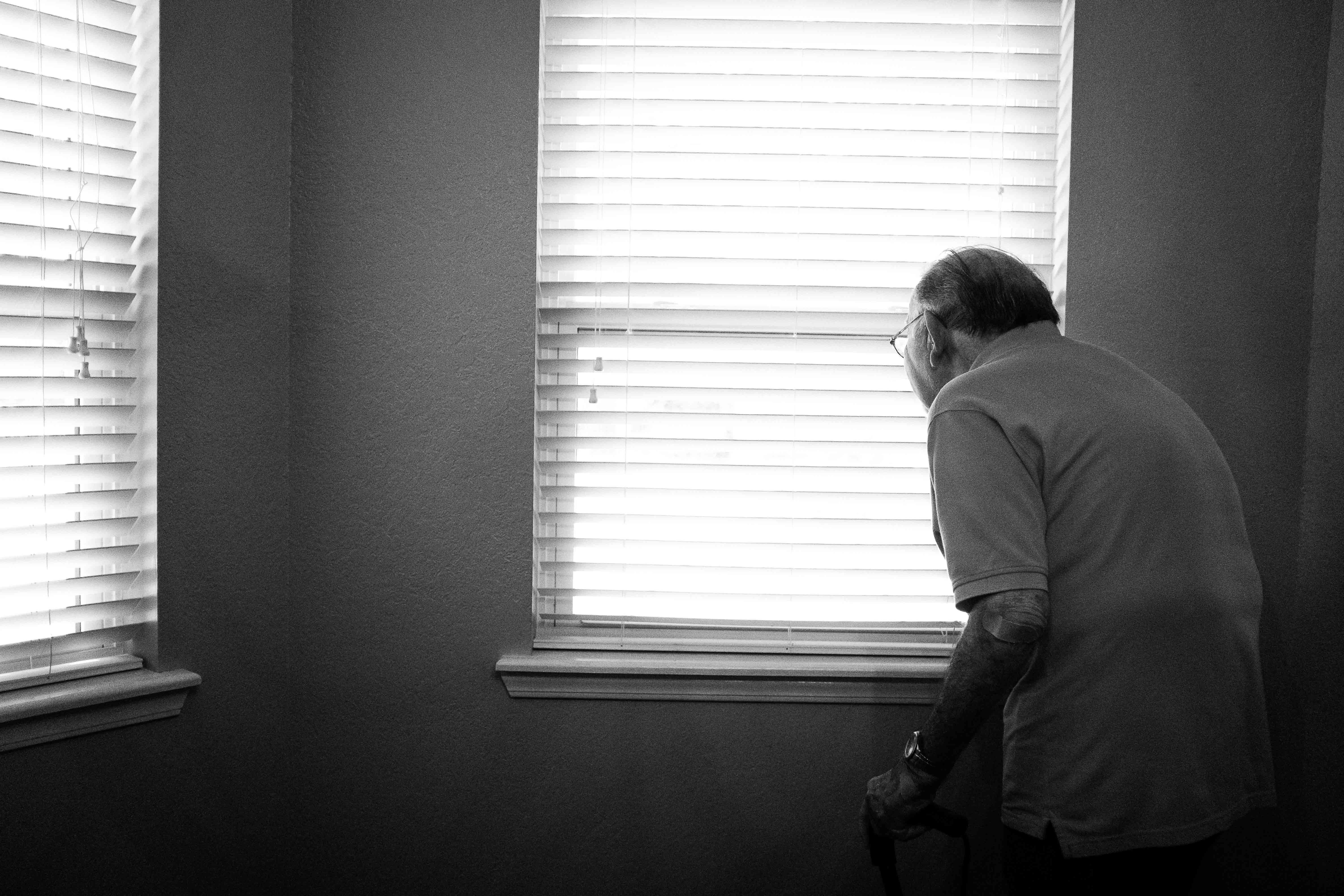 Lonely senior citizen looking out of the window